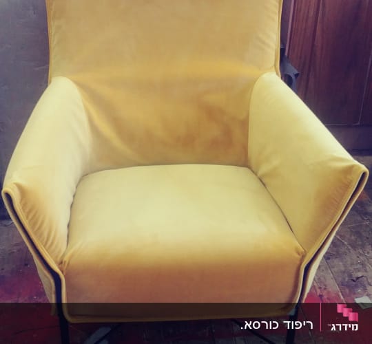 כורסה מרופדת בצבע צהוב על רצפת עץ
